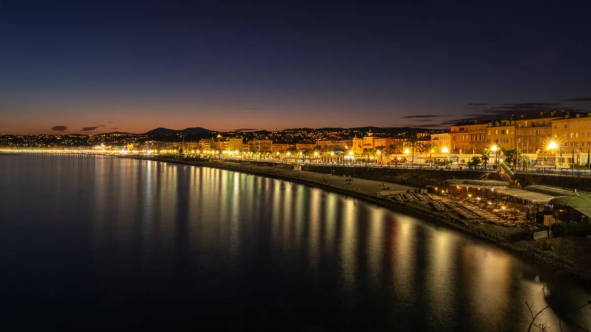 La promenade des Anglais à l'heure bleue : les lumières de la ville se reflètent dans la baie des Anges.