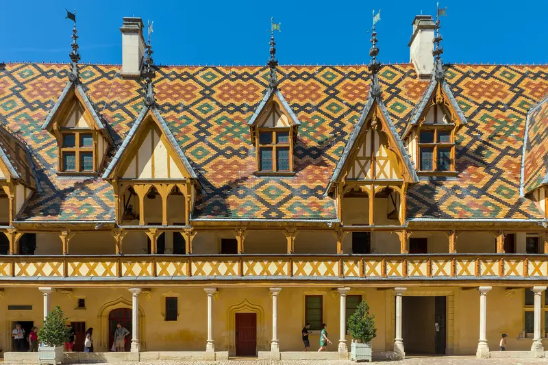 La cour de l'Hôtel-Dieu de Beaune et ses toits de tuiles vernissées aux motifs colorés.