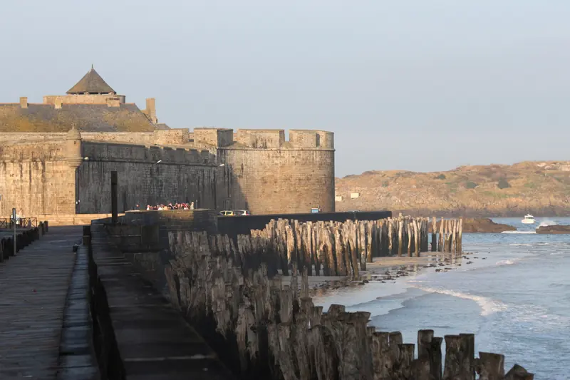 Les remparts et le château de Saint-Malo au bord de la mer, avec les brise-lames en bois de la plage du Sillon.